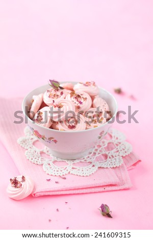 Rose Meringue Cookies in a bowl on a pink napkin, on a light pink background.