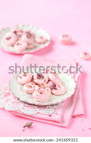 Rose Meringue Cookies on two plates on a pink napkin, on a light pink background.