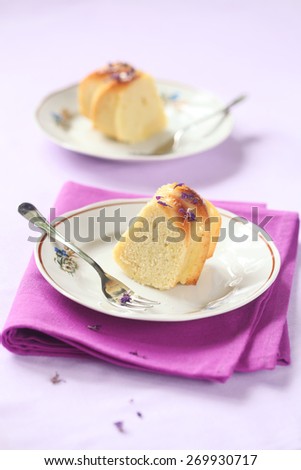 Two Pieces of Lemon Cake on two plates, and bright purple napkin on a light purple background.