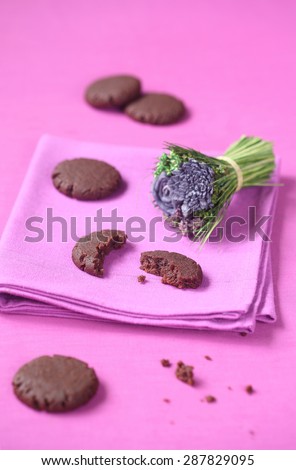 Vegan Chocolate Raspberry Cookies and a little dried flower bouquet, on a purple napkin and purple background.