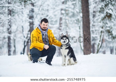 Man and dog in the snow in a forest in the afternoon