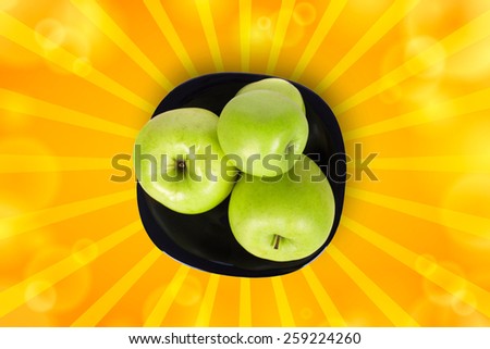 Four green apples on a black plate with a white background