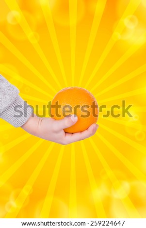 The hand of a little boy holding an orange