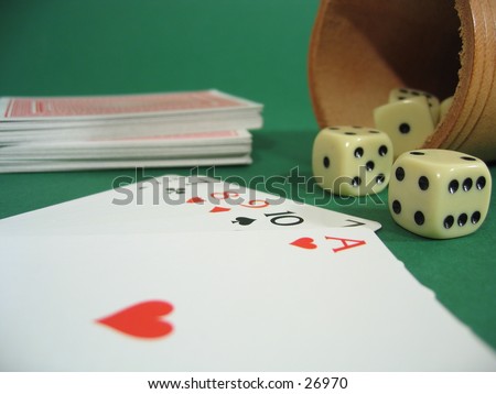 A deck of cards and a dice box with dice on green background.