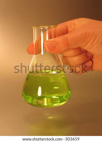 A conical (Erlenmeyer) flask with green liquid lifted by a hand.