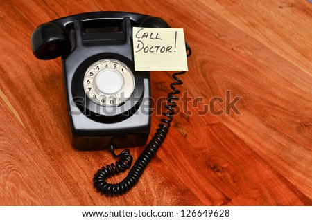 Retro black telephone with reminder note to call the doctor