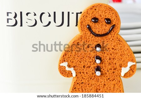 Ginger bread man standing next to biscuit tin