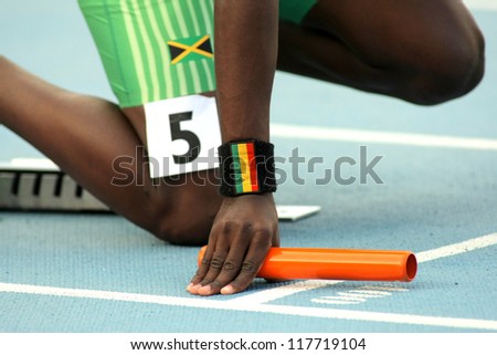 Athlete with a baton on the start of relay event