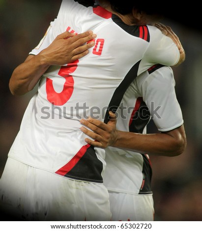 Male Soccer players in white t-shirt standing hugging united and showing team spirit in a game on the field outdoors