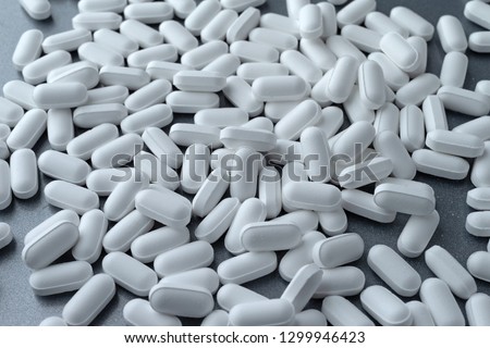A group of potassium gluconate tablets on a gray metal background illuminated with natural lighting.