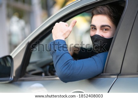 Portrait of young man driving his car and showing thumb up. New normal lifestyle concept.