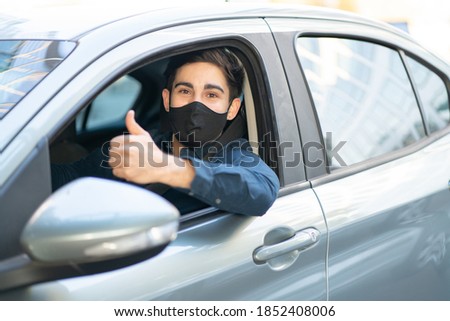 Portrait of young man driving his car and showing thumb up. New normal lifestyle concept.