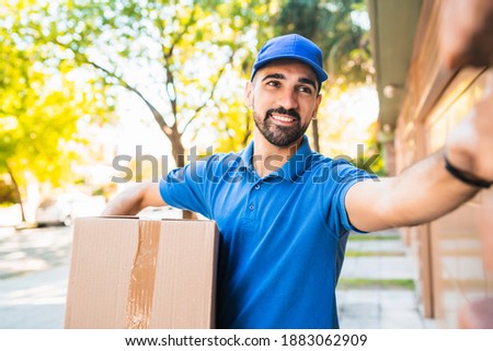 Delivery man carrying packages while making home delivery.