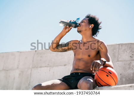 Athletic man drinking water after work out outdoors.