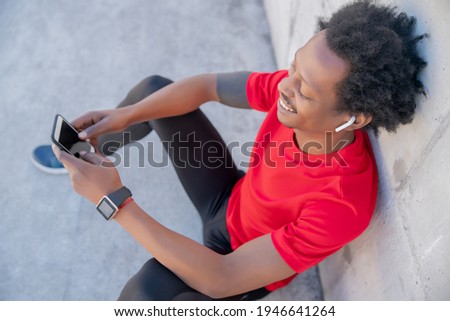 Athletic man using his mobile phone outdoors.