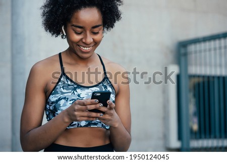 Athletic woman using her mobile phone outdoors.
