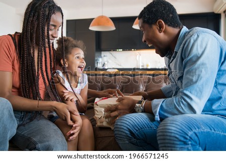 Little girl receiving gift from her parents.