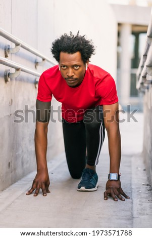 Athlete man in start position preparing to run outdoors.