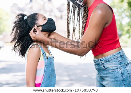 Mother putting a face mask on her daughter.