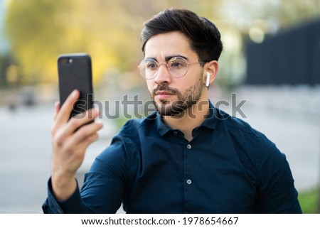 Young man using face id for unlock mobile phone outdoors.
