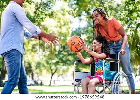 Girl in a wheelchair playing basketball with her family.