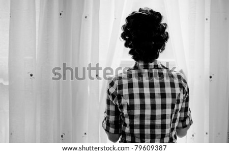 Girl looking through the window curtains