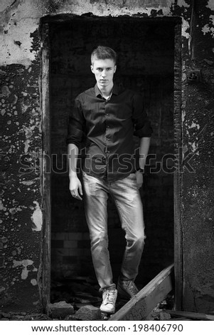 Young attractive hansome man on abandoned background. Black and white photo