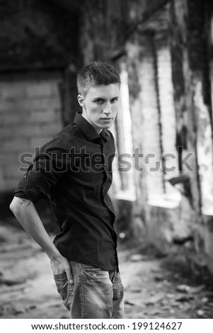 Young attractive man on abandoned background. Black and white photo