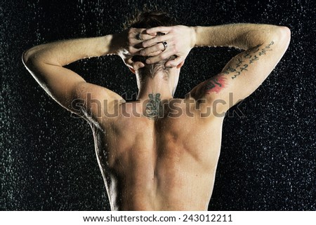 Naked back. Attractive man under drop water