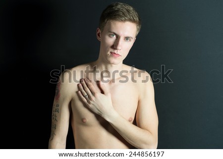Young thin man, naked torso on black background