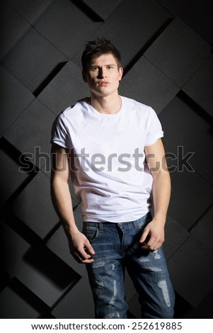 Man in white t-shirt and jeans on grey background