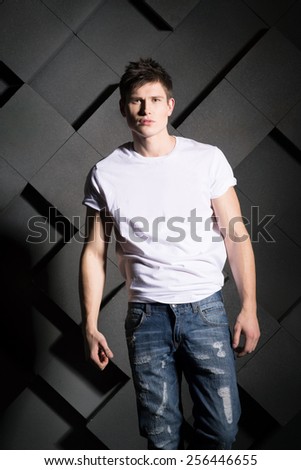 Man in white t-shirt and jeans on grey background