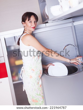 the girl apron washes the dishes in the sink