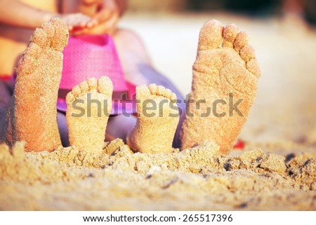 feet in the sand at sunset , adult and child, family