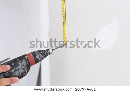 Fixing and renovating home interior. Man holds drill machine.