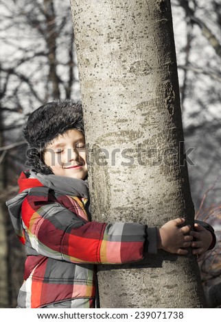 Boy hugging a tree, listening the sounds of the Nature. Taking care of the forest.