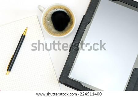 close-up of tablet, a blank notebook, a pen and a cup of coffee
