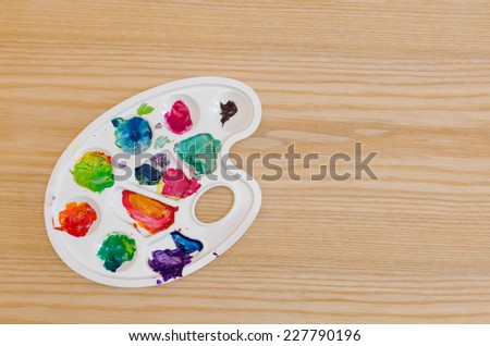 white palette with smudges of paint on a wooden table