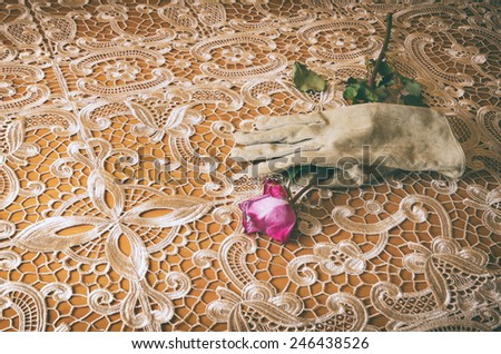 female glove holding a rose on an elegant table cloth
