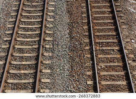 two parallel railway tracks with two colored gravel and stones in between