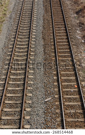 two old parallel railway tracks going into distance with two colored gravel and stones in between