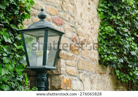 retro style lantern and vines on an old stone wall