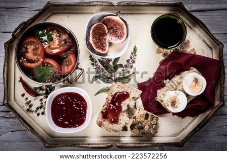 Breakfast on a tray with bread, marmelade, tea, tomatoes, salad ans figs