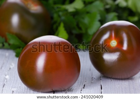 Kumato, black tomatoes on wooden background