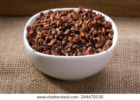 sichuan or japanese pepper in white bowl on linen background