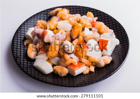 Mixed frozen seafood on black plate and white background