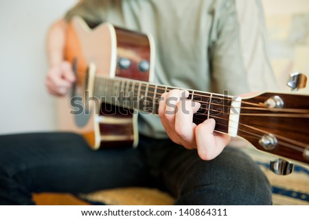 Guitar player - Young man playing acoustic guitar in his room.