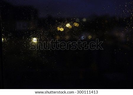 rain on the window and blurred shiny light in background