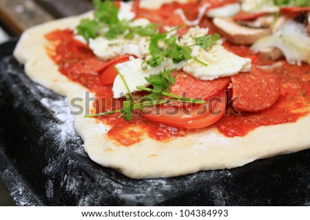 A homemade pepperoni sausage, mozzarella cheese, tomato, mushroom and onion pizza, with fresh coriander, set on a homemade pizza dough base with a homemade tomato sauce.