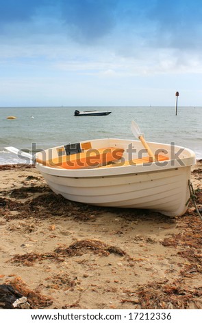 White and Yellow boat on sandy beach. Beach with washed up seaweed, sea horizon in background. Location Christchurch, Dorset UK.